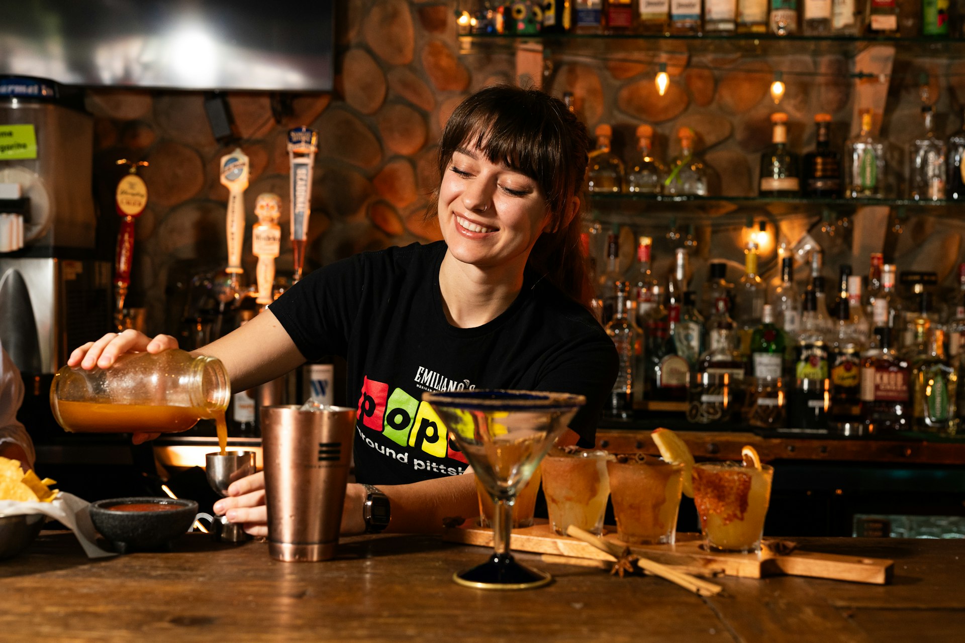 A bartender pouring a drink with focus behind the bar, the composure strong managers bring to the floor